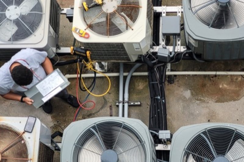 HVAC technician performing preventive maintenance on an air conditioning unit